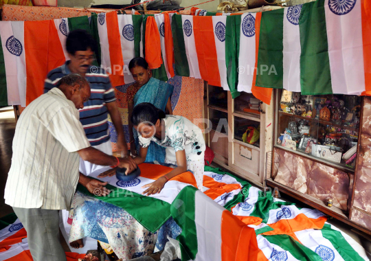 O n   t h e   u p - c o m i n g   I n d e p e n d e n c e   D a y   o f   I n d i a   a   m a n   b u s y   w i t h   h i s   f a m i l y   o n   m a k i n g     I n d i a n   F l a g s   t o   f u l 